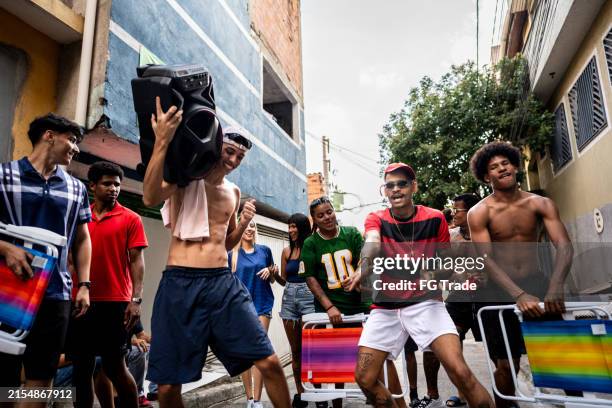 amigos bailando y caminando por la calle escuchando música en un estéreo en una favela en brasil - música funk fotografías e imágenes de stock