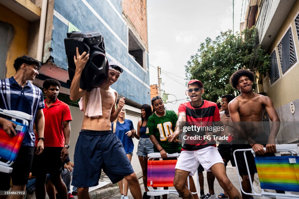 Friends dancing and walking the street listening music on a stereo on favela in Brazil