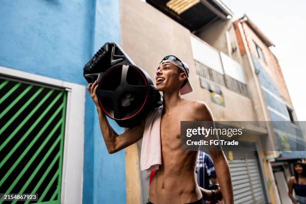 giovane felice che cammina portando uno stereo ascoltando musica per le strade della favela in brasile - funky foto e immagini stock