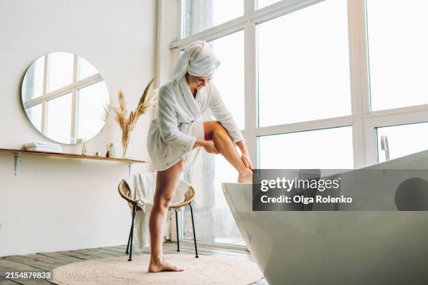 leg massage and healthy skin: woman applies cream to legs after a bath - leg stock pictures, royalty-free photos & images