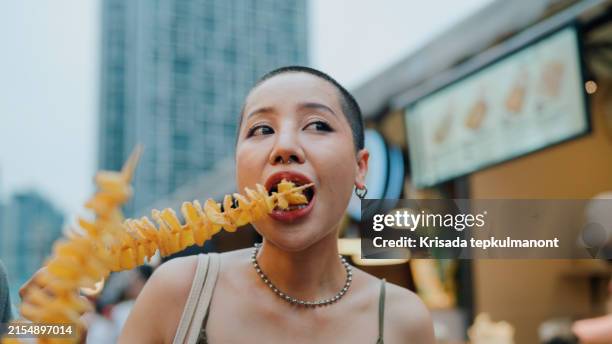 young asian couple tourist eating crispy potato chips at the street food. - streetfood stock-fotos und bilder