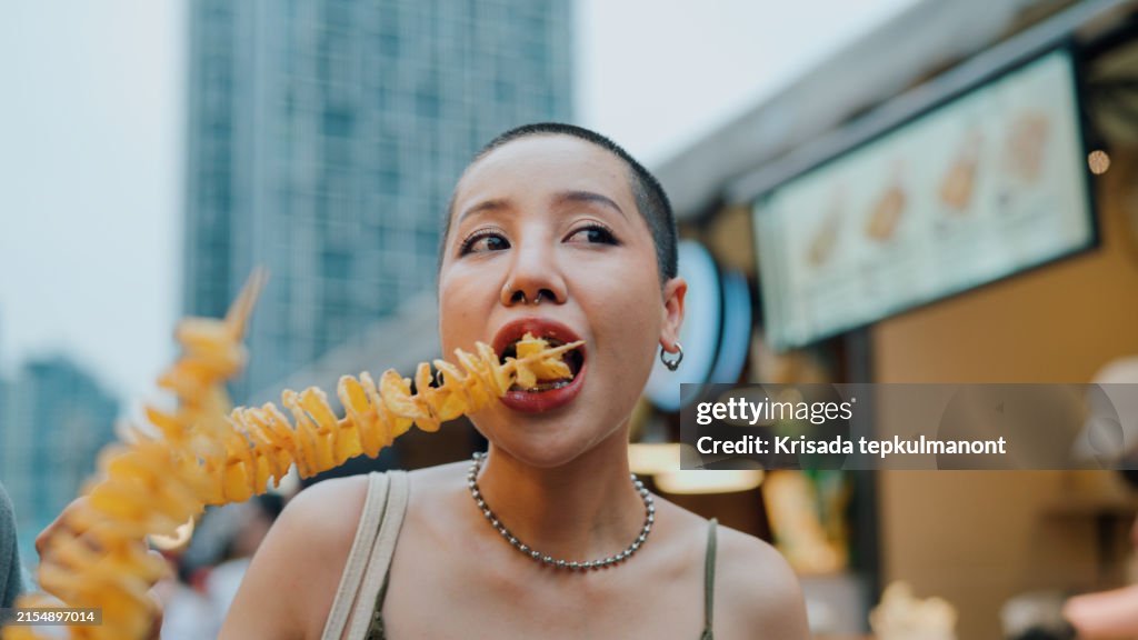 Young asian couple tourist eating Crispy Potato Chips at the street food.