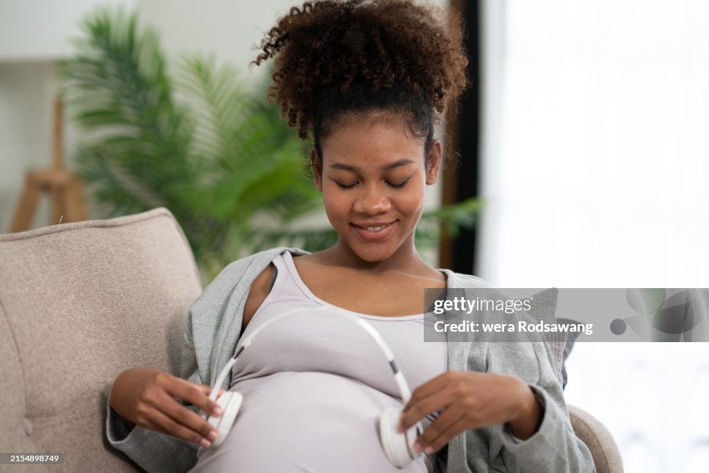 Pregnant woman using headphone listen music for baby brain development, playing music for baby in womb