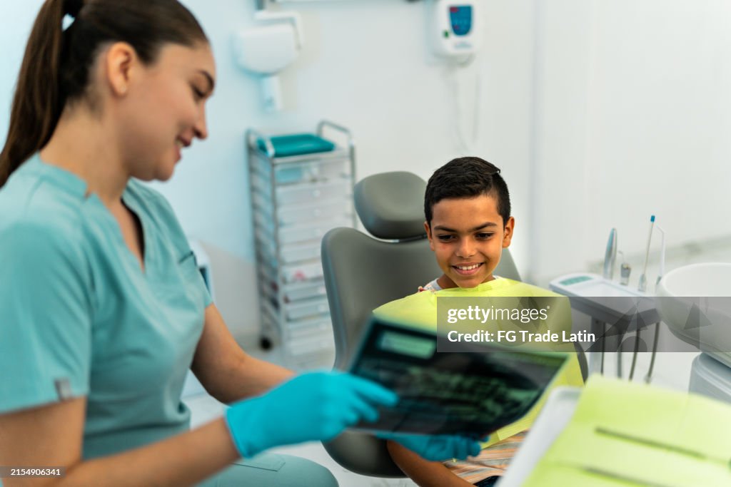 Young dentist woman showing the thooth x-ray to child patient at dentist office