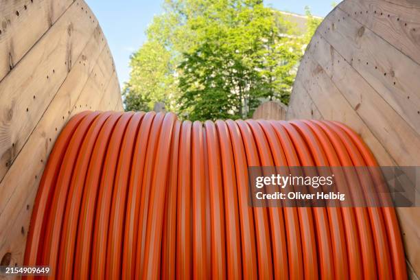 a long orange high speed internet fiber cable is shown in the image. the cable is wrapped around a wooden pole. - ondergrond stockfoto's en -beelden
