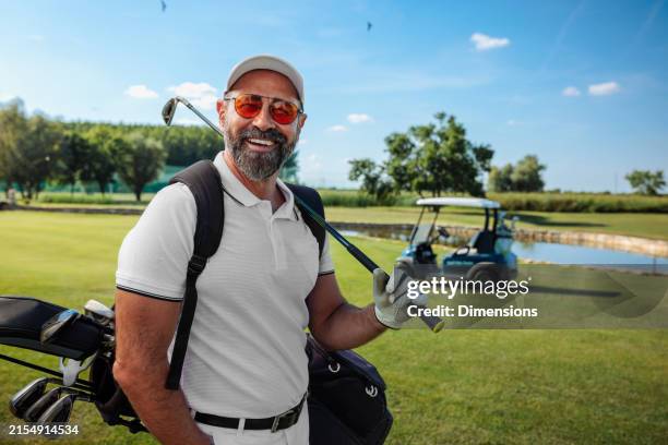 happy mature golfer standing on the field and smiling to the camera - golf stock pictures, royalty-free photos & images