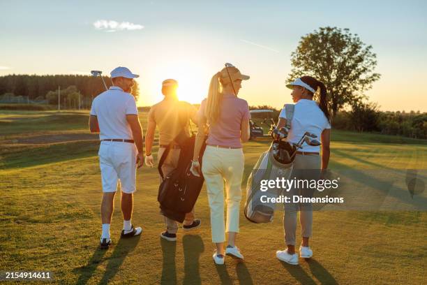 friend group is strolling down the golf court - golfista imagens e fotografias de stock