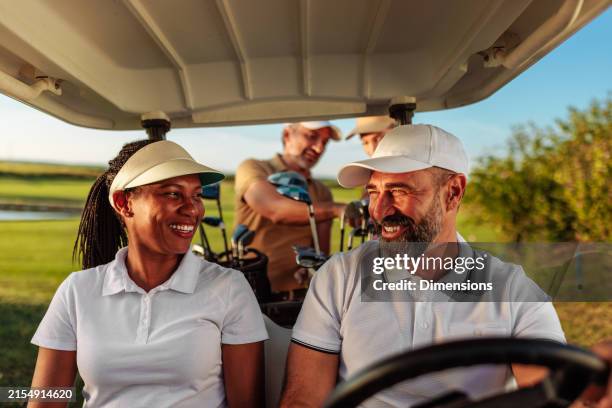 couple sitting and smiling in a golf cart - golf driver cap stock pictures, royalty-free photos & images