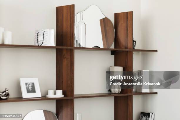 wooden bookcase with books, mirror lamp and decorations in white interior. - accessorio personale foto e immagini stock