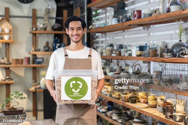 pottery artist holding eco-friendly packaging box in studio - circulaire economie stockfoto's en -beelden