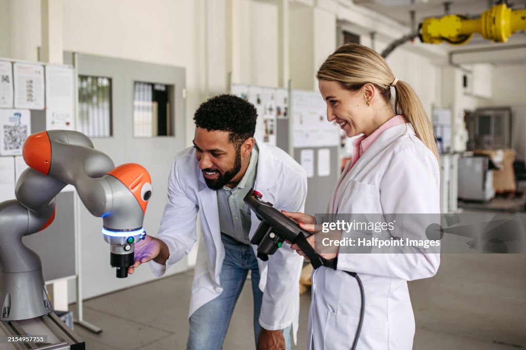 Robotic engineer colleagues working on robotic knee replacement surgery project, adjusting robots settings. Concept of robotics, engineering and computer science in healthcare.