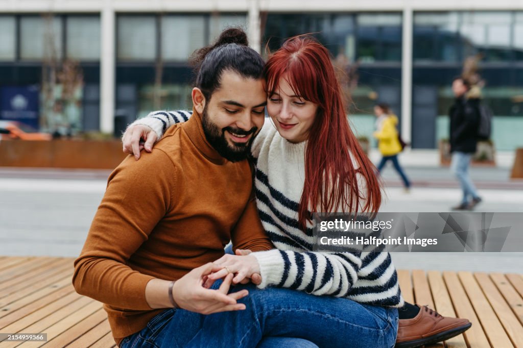 Engagement. Beautiful couple looking at ring on woman hand, after she said yes to her future husband. Together during cold spring, autumn day.