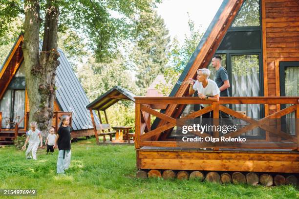 summer activities with kids: family enjoys blowing bubbles and playing by the wooden house in nature. - glamping stock-fotos und bilder