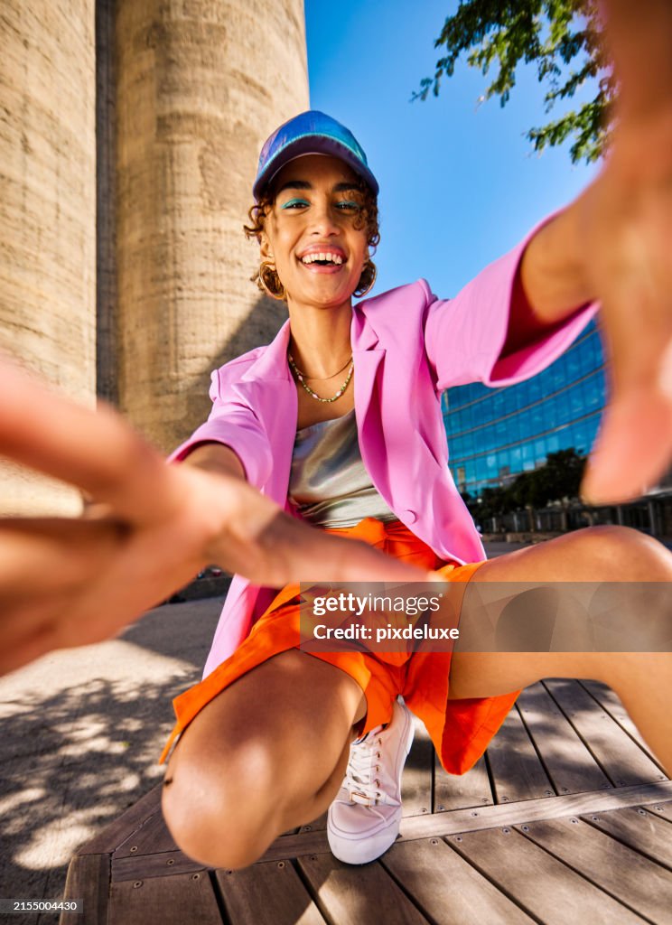 Gen Z female smiling and looking through a hand frame gesture outdoors in an urban environment. Low angle shot.
