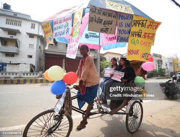 Voters ride a rickshaw with slogans on voting awareness during seventh and last phase of Lok Sabha election at Congress Maidan on June 1, 2024 in...