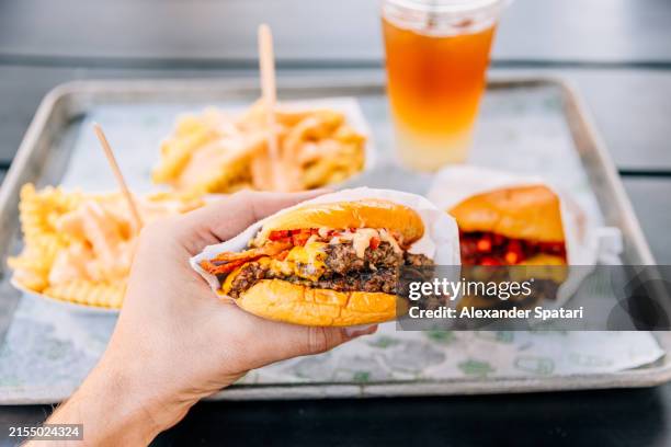person eating double cheeseburger with bacon at a fast food joint, personal perspective view - comida rapida fotografías e imágenes de stock