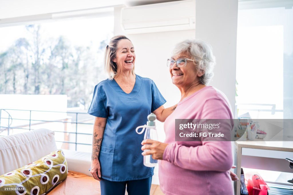 Happy senior woman and physical therapist at home