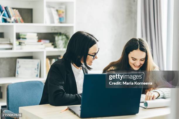 teacher assisting girls in classroom. - schoolbegeleider stockfoto's en -beelden