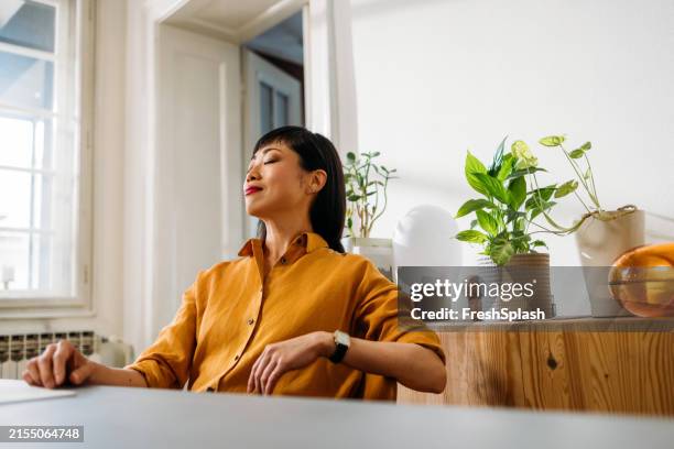 woman relaxing at home desk with indoor plants - mental wellbeing stock pictures, royalty-free photos & images