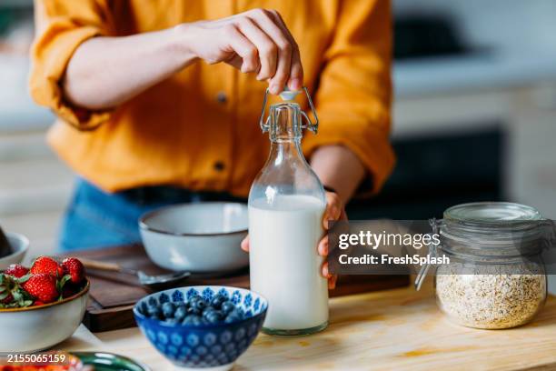 personne préparant un petit-déjeuner sain avec du lait frais et des baies - produit laitier photos et images de collection