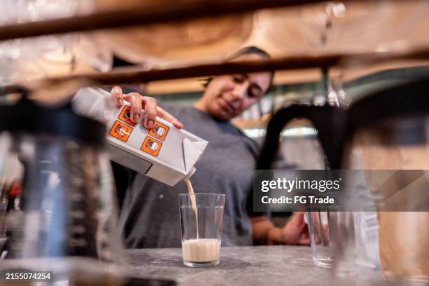 cafeteria-mitarbeiter, der in der cafeteria einen kaffee mit milch zubereitet - hafermilch stock-fotos und bilder