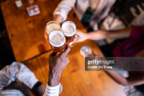 primo piano di colleghi che fanno un brindisi celebrativo che bevono birre al bar - happy hour foto e immagini stock