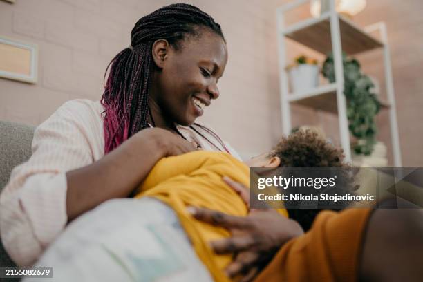 young mother breastfeeding - breastfeeding stock pictures, royalty-free photos & images