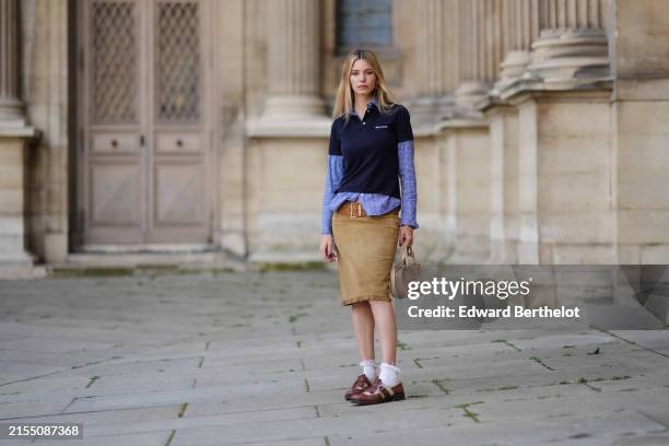 Natalia Verza wears a full Miu Miu look, a dark navy blue polo shirt, a blue shirt / layered top, a large suede belt, a knee length fringed skirt in...