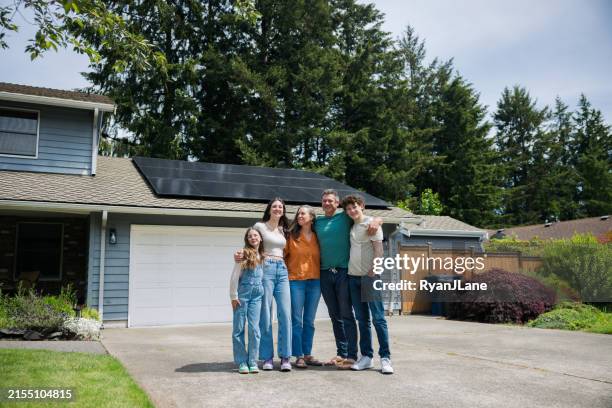 familia feliz junta frente a una casa equipada con energía solar - herramientas industriales fotografías e imágenes de stock
