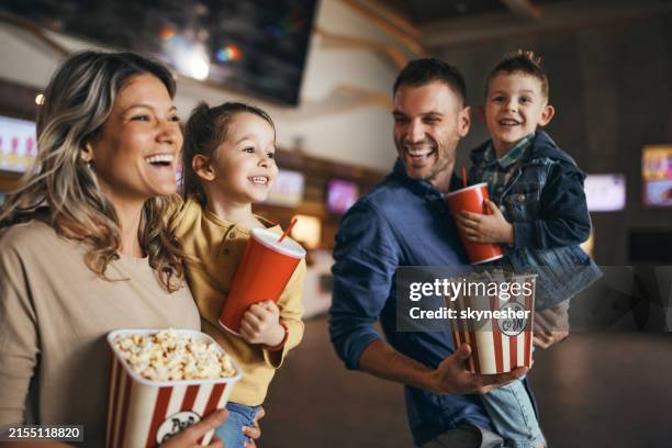 jeune famille heureuse avec du maïs soufflé et des boissons au cinéma. - entertainment photos et images de collection