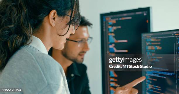 primo piano del team di ingegneri del software impegnato nella risoluzione dei problemi e nell'analisi del codice per lo sviluppo web in un ufficio moderno. sviluppatore software, intelligenza artificiale e programmazione. - programmazione televisiva foto e immagini stock