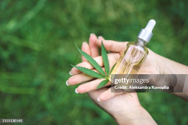hands holding cbd oil dropper with cannabis leaf - dropper bottle stock pictures, royalty-free photos & images