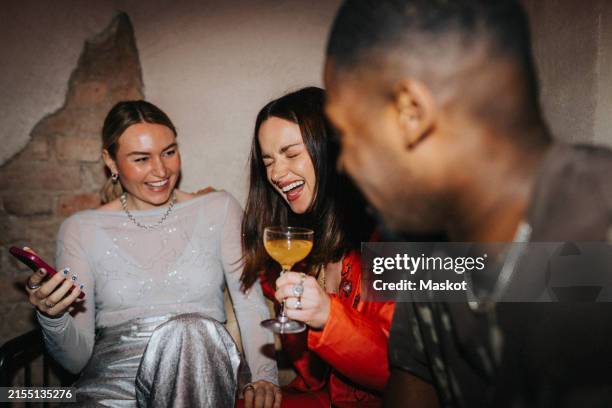 cheerful woman holding drink glass while sitting with male and female friends at bar - rubbing alcohol stock pictures, royalty-free photos & images