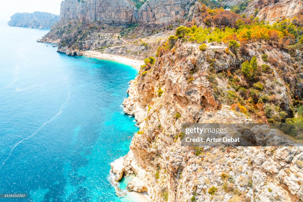 Aerial view flying above a paradise beach with rocky terrain on the Costa Blanca in the Comunidad Valenciana. Spain.