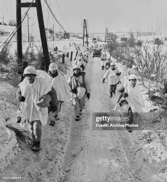 Column of American soldiers from C Company, 16th Infantry Regiment, Ist Infantry Division , United States First Army outfitted in white camouflage...