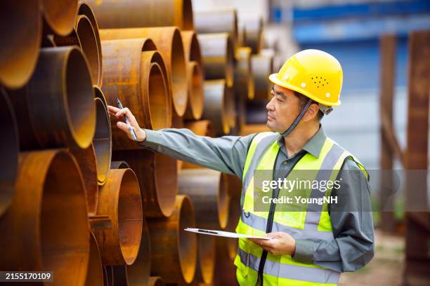 asian middle-aged man wearing a safety helmet, working in a steel factory - steel mill stock pictures, royalty-free photos & images