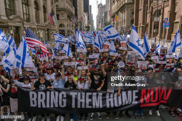 People, including the families of hostages, walk at the front holding a 'Bring them home now' sign at the the Israel Day on Fifth parade on June 2,...