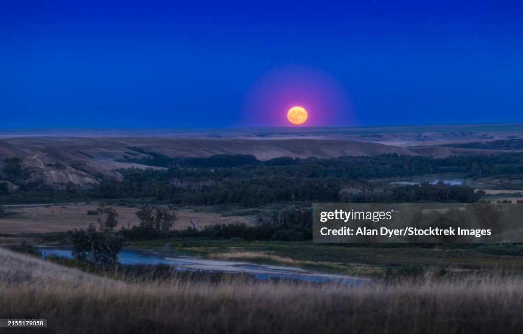 Supermoon rising over the Bow River and valley in southern Alberta, Canada