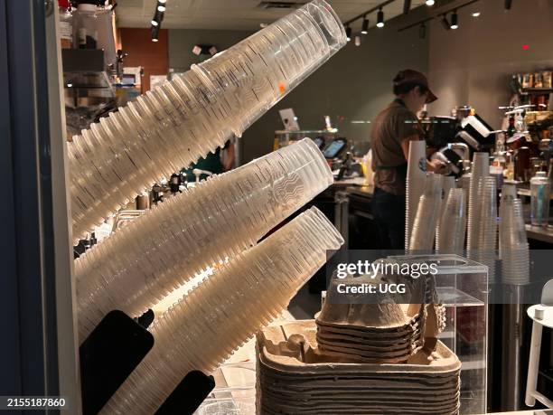 Mobile order delivery pick up window with stacks of single use plastic cups at Starbucks coffee shop, Queens, New York.