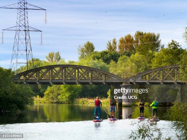 Abandoned railway bridge over the Thames at Kennington, with early paddle boarders.