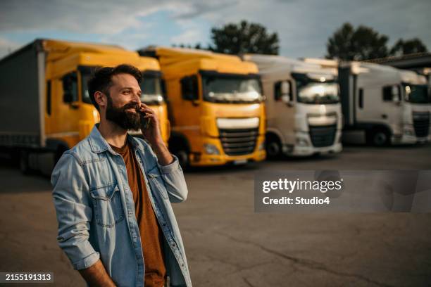 truck driver with a phone on a parking lot - vrachtwagenchauffeur stockfoto's en -beelden
