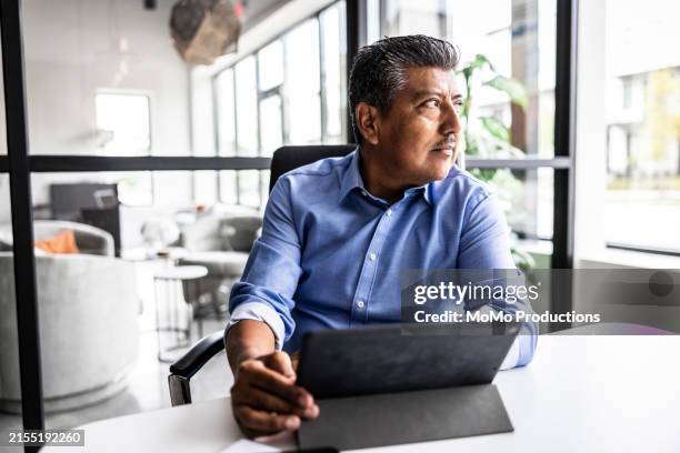 businessman looking out window in modern office - prejudice stock pictures, royalty-free photos & images