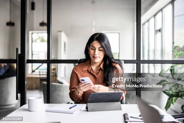 businesswoman using smartphone in modern office - mirar hacia abajo fotografías e imágenes de stock