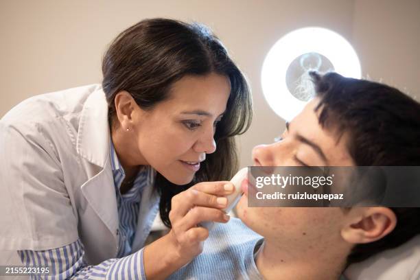 female dermatologist examining her patient with a dermatoscope - dermatology stock pictures, royalty-free photos & images