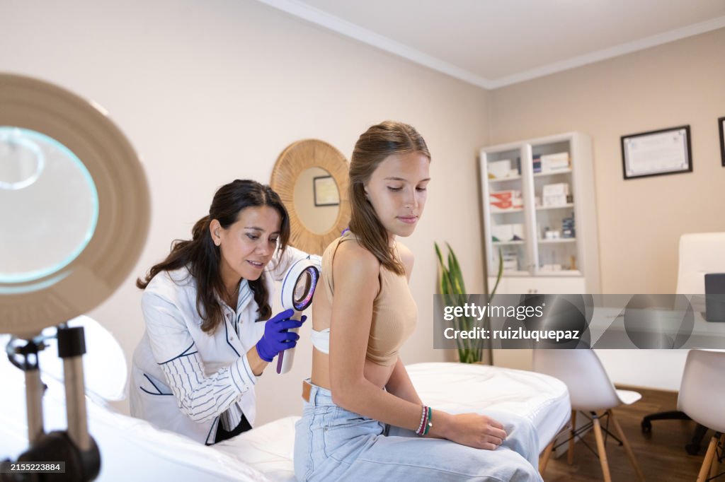 Dermatologist examining her patient with a dermatological magnifying glass