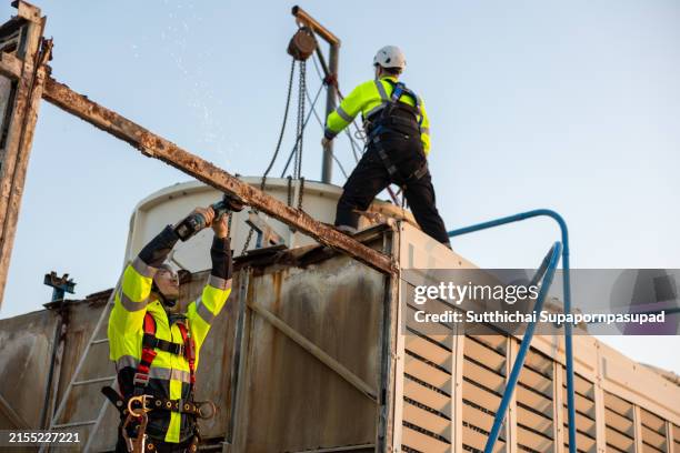 rooftop demolition project: two engineers at work on dismantling a cooling tower. exploring the complexities of industrial engineering, safety protocols, and team effort required for building renovation and maintenance in a cityscape - compressor stock pictures, royalty-free photos & images