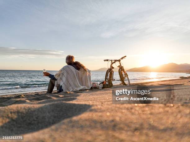 mature couple enjoy drinks on beach - early retirement stock pictures, royalty-free photos & images