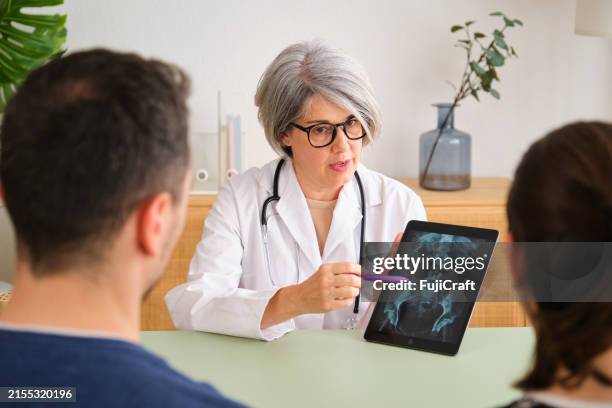 un médecin montre à un patient une tomodensitométrie de sa colonne vertébrale - hanche photos et images de collection