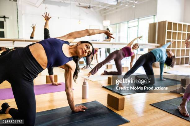 young woman doing yoga pose during yoga class - fitnessausrüstung stock-fotos und bilder