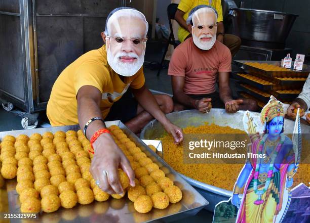 Workers are seen wearing masks of Prime Minister Narendra Modi as they prepare sweets inside a sweets-making workshop ahead of the Lok Sabha election...